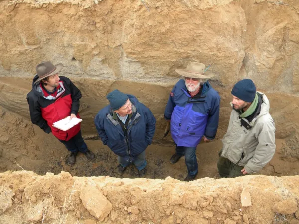 Four men standing in a trench in red rock