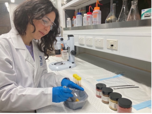 PhD student Maedeh Darzi in the lab grinding standard ochre samples in a mortar and pestle