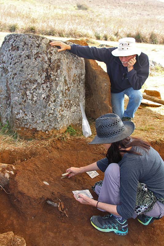 Excavating beneath a large sandstone disc at the Plain of Jars, Laos