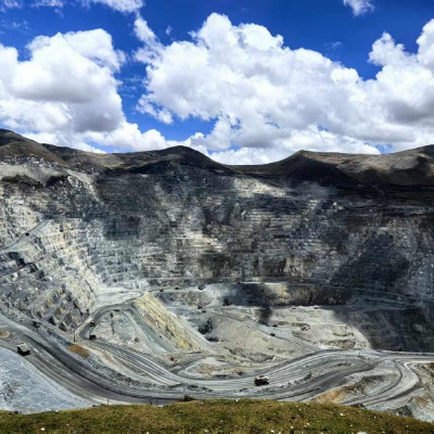 View into an open cut mine against a blue clouded sky.