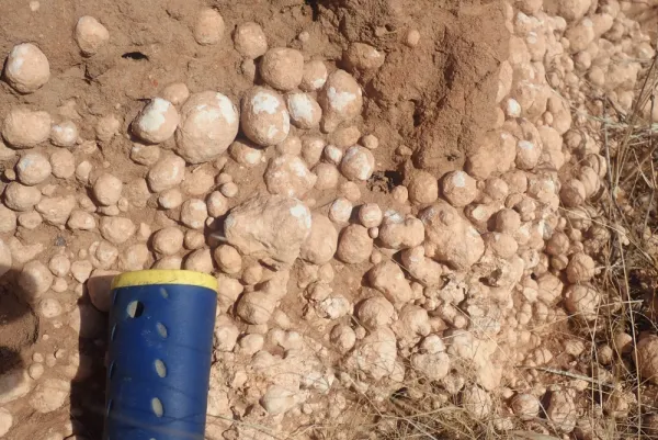 Small round rocks packed tightly together in each, handle of hammer for scale.