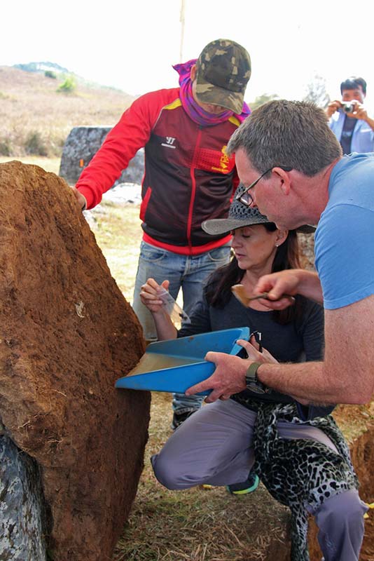 Members of the Plain of Jars team taking samples from beneath a large sandstone disc at Site 1 Laos