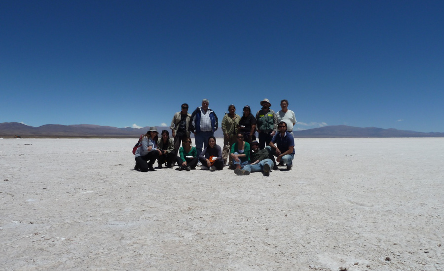 Group of people standing on flat plateau with mountains in the far distance.