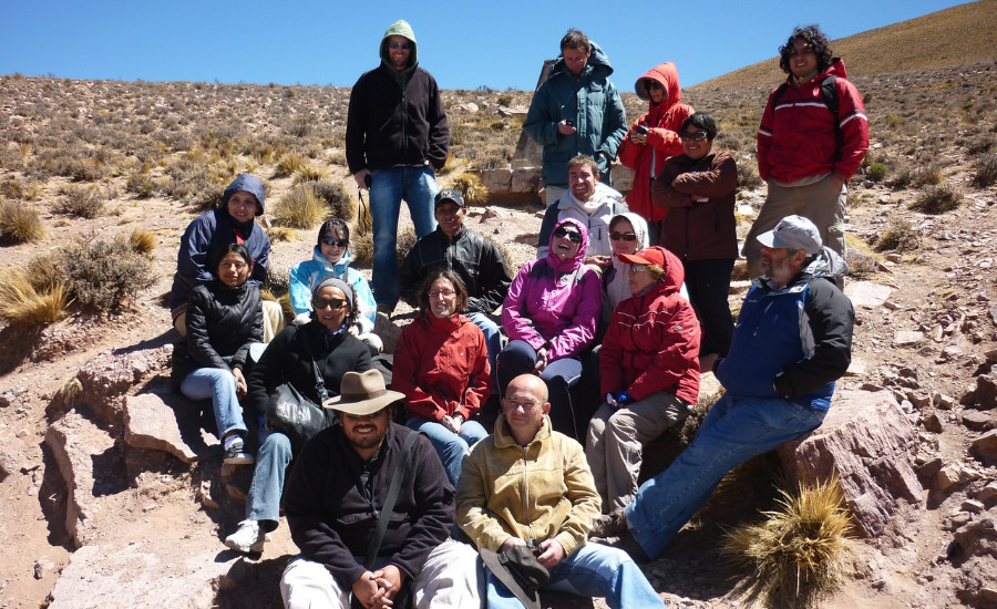 Group of people sitting on a rocky hillside.